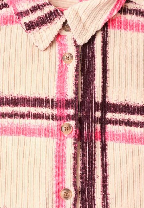 Gros plan sur une chemise en velours côtelé à carreaux roses et foncés avec boutons en bois.