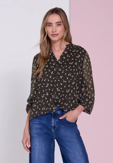 Langarm Chiffon-Bluse mit Split Neck black coffee Frau in dunkler Bluse mit Muster und blauen Jeans vor zweifarbigem rosa Hintergrund.