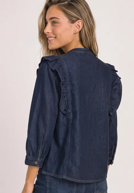 Junge Frau im Profil trägt dunkelblaue Denim-Bluse mit Rüschen an den Schultern.