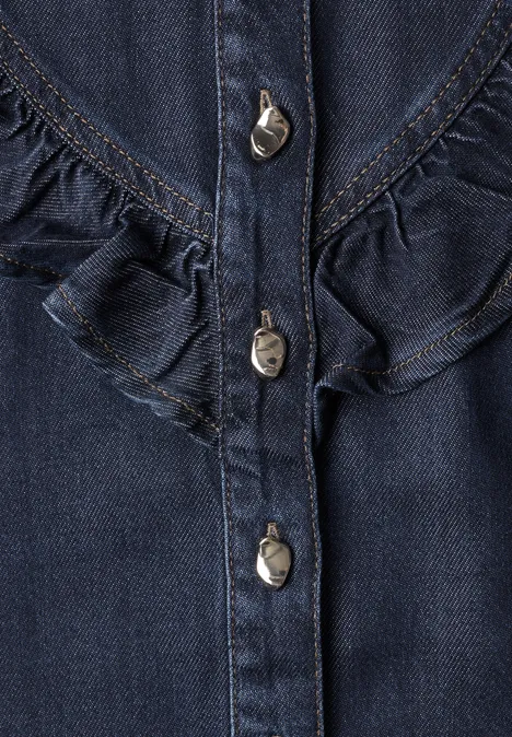 Nahaufnahme eines dunkelblauen Jeansoberteils mit Metallknöpfen und Rüschen.