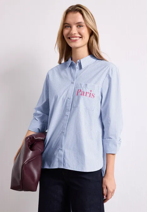 Langarm Hemdbluse mit Wording Detail northern blue Frau trägt hellblaue Bluse mit Schriftzug "Paris" und hält eine Tasche.