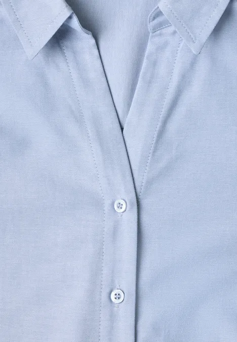 Gros plan d’une chemise en coton bleu clair avec col et boutons apparents
