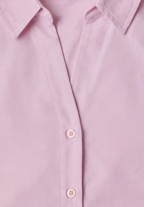 Gros plan sur une chemise rose pâle à col et patte de boutonnage.