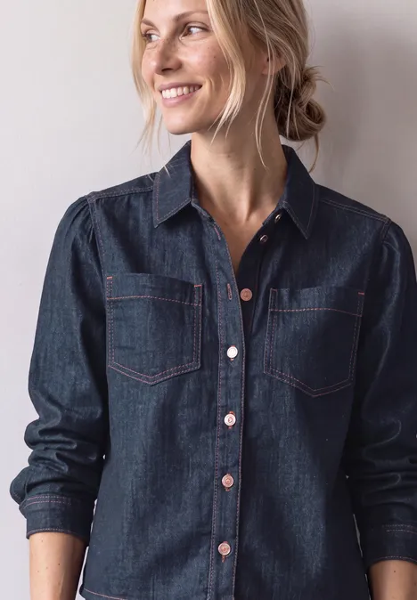 Portrait d'une femme souriante en veste en jean sur fond clair.