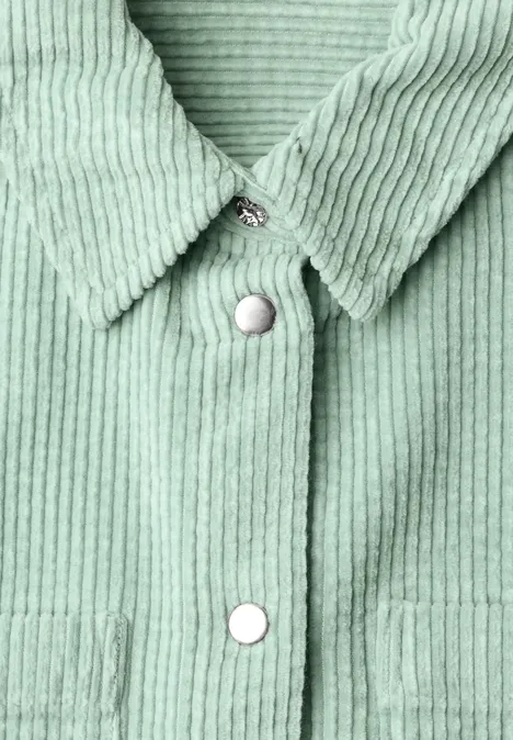 Detailaufnahme eines mintgrünen Cordhemds mit Kragen und weißen Druckknöpfen.