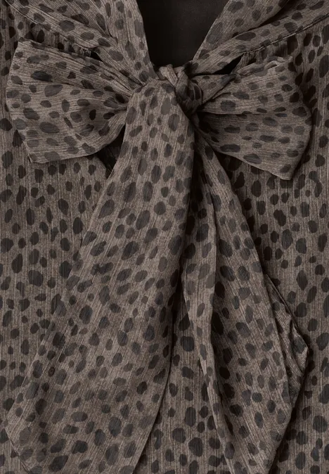 Tissu gris foncé à pois noirs irréguliers, noué en un nœud décontracté.