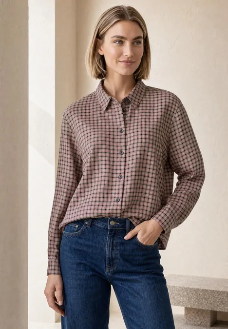Langarm Hemdbluse mit Karomuster warm blush Frau trägt karierte Bluse und blaue Jeans, steht lächelnd vor hellem Hintergrund.