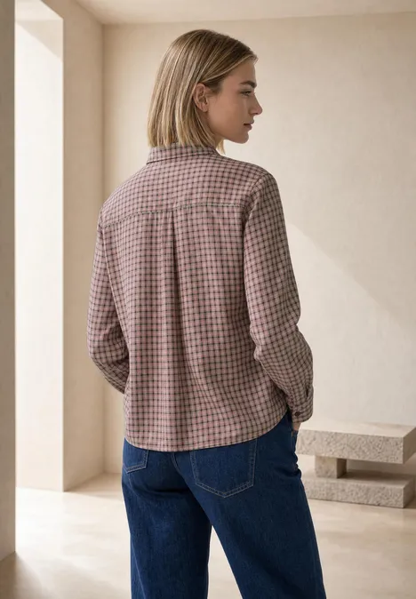 Langarm Hemdbluse mit Karomuster warm blush Frau von hinten in kariertem Hemd und blauen Jeans vor schlichter Wand.