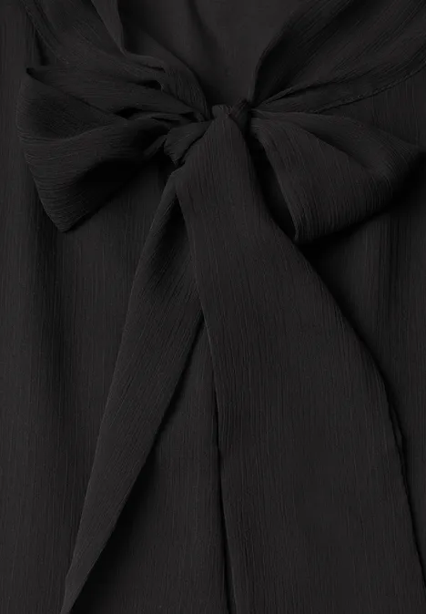 Tissu noir texturé à fines côtes, noué en un élégant nœud papillon.