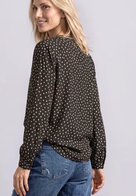 Langarm Tunika mit Split Neck und Print black coffee Frau mit schwarzer gepunkteter Bluse und Jeans, schaut über die Schulter.