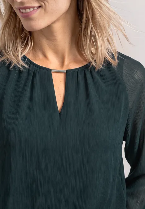 Dunkelgrüne Bluse mit feiner Struktur, langen Ärmeln und kleinem Schlitz am Ausschnitt mit Metallsteg.