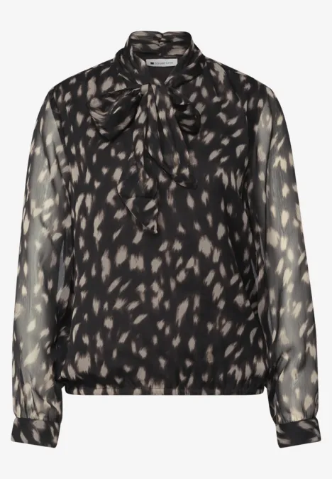Blouse noire transparente à motifs léopard discrets et col noué.