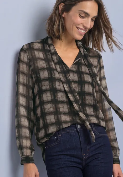 Chiffonblouse met strikdetail sanded amber Vrouw in transparant ruitblouse met strik en hoge taille jeans, glimlachend voor een effen achtergrond