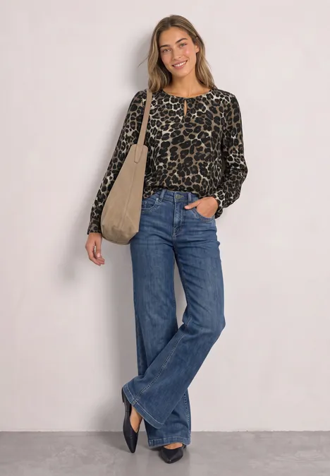 Junge Frau trägt Leo-Print-Pullover, weite Jeans und Tasche