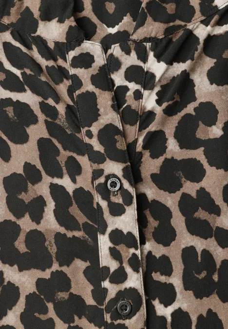 Nahaufnahme eines Kleidungsstücks mit Leopardenmuster und schwarzen Knöpfen.