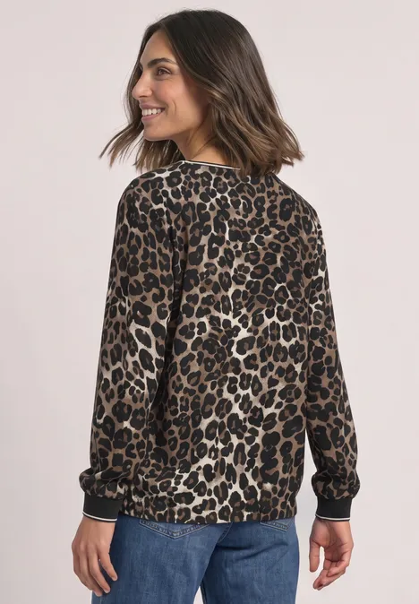 Frau in Leoparden-Print-Pullover und Jeans, von hinten fotografiert, lässiger Look.
