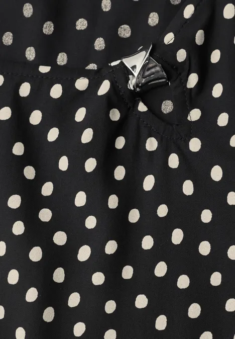 Zwarte stof met witte polkadots en een klein decoratief strikje.