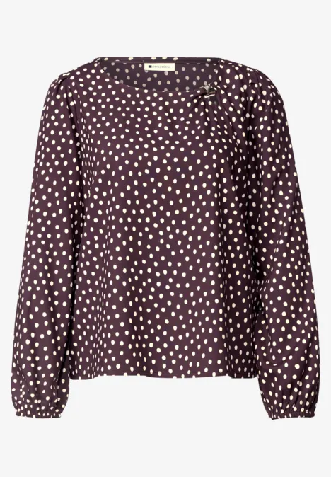 Donkerpaars blouse met lange mouwen en witte stippen.