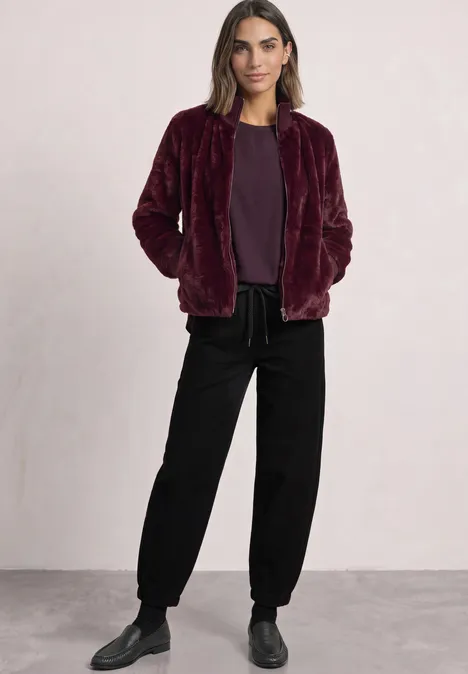 Femme portant une veste teddy bordeaux, tee-shirt assorti et pantalon noir ample