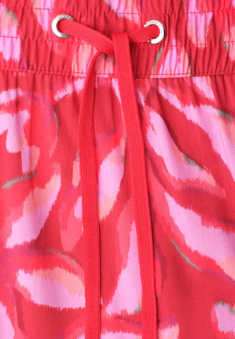 Rode stof met roze-witte abstracte patronen, elastische taille met rood koord en oogjes.