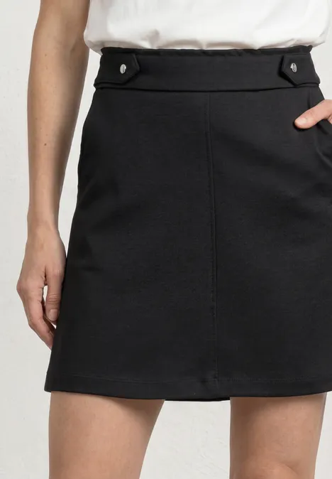 Jupe noire au-dessus du genou avec poches décoratives à la taille.