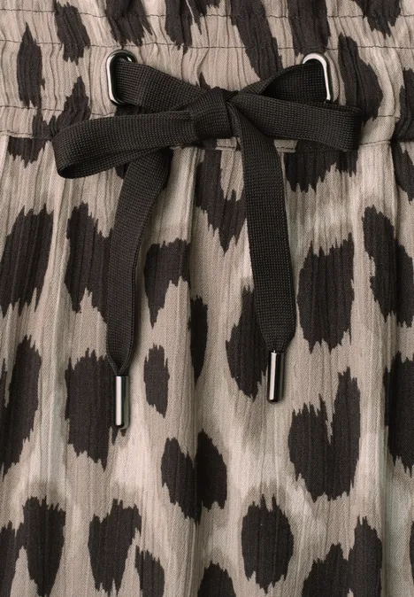 Jupe au genou à imprimé et à volants timeless beige Gros plan d'un tissu imprimé léopard gris et noir, orné d'un cordon plat noir noué en boucle.