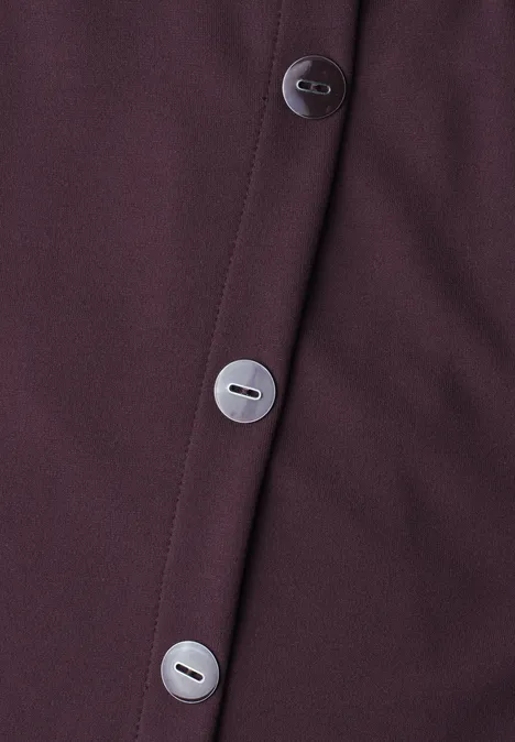 Gros plan d'un tissu violet foncé avec trois boutons argentés alignés.