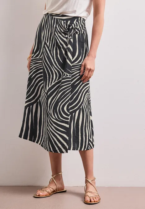 Schwarz-weißer Zebra-Midirock mit Taillenschnürung und flachen Sandalen.