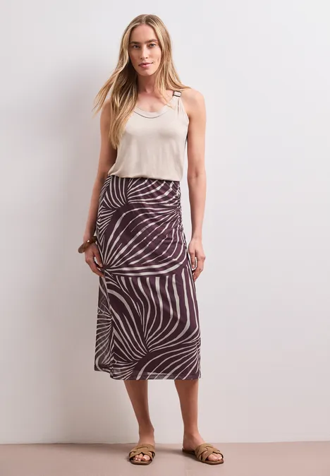 Midi-Rock aus Mesh mit Print rustic rouge Frau mit weißem Top und Rock im Zebra-Muster.