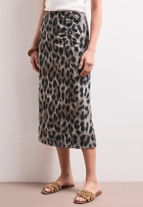 Midi-Rock aus Mesh mit Print timeless beige Frau trägt einen knielangen Bleistiftrock mit Leopardmuster und goldenen Sandalen.