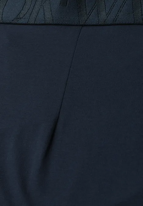 Nahaufnahme einer Person in dunkelblauen, eng anliegenden Leggings mit sichtbarem Nike-Logo am Bund.