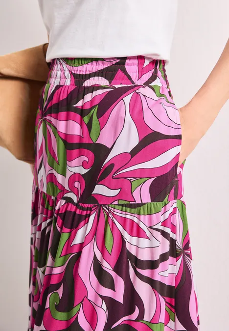 Lang geschnittener Rock mit elastischem Bund und auffälligem psychedelischem Muster in Pink, Lila und Grün.