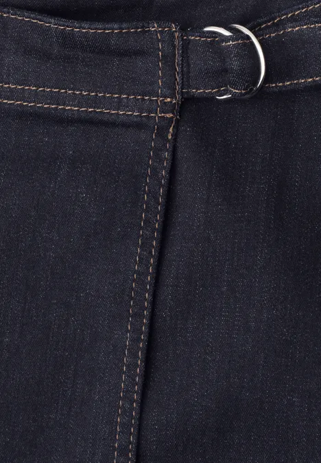 Dunkle Jeans mit Gürtel und silbernem D-Ring an der Taille.