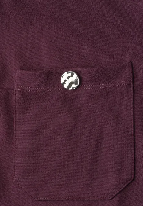 Bordeauxroter Stoff mit aufgesetzter Tasche und silbernem Knopf.