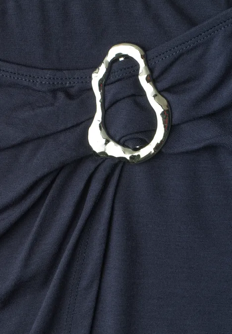 Dunkelblauer Stoff mit silbernem, dekorativem Ring, der Falten bildet.