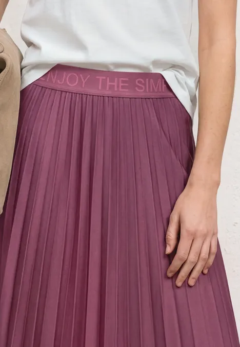 Midirock in Plisséestruktur dark clouded blush Ein plumfarbener, plissierter Midirock mit elastischem Bund 'ENJOY THE SIMPL...' und weißem Shirt.