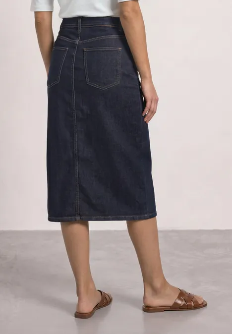 Dunkelblauer Jeans-Midirock mit Rückenschlitz und Taschen, dazu braune flache Sandalen.