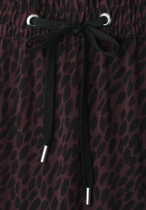 Dunkelroter Stoff mit schwarzem Leopardenmuster und Schnürbund.