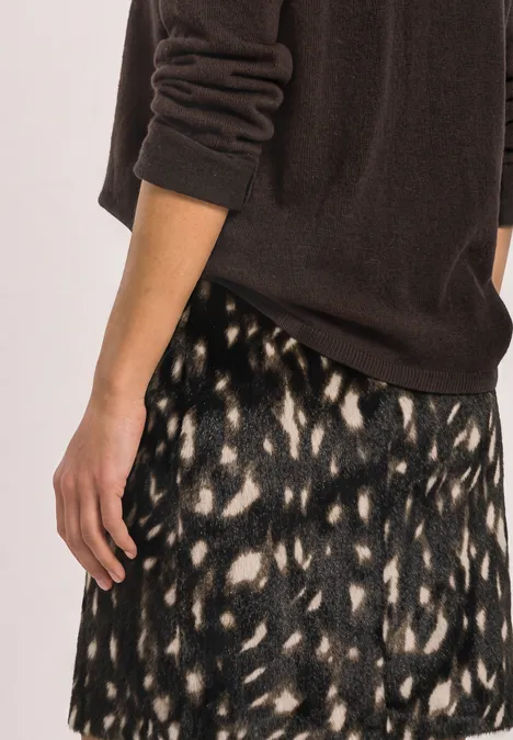 Knielanger Fake-Fur Rock mit Muster Black Frau trägt braunen Pullover und gemusterten Rock in Schwarz und Creme mit abstraktem Leopardenmuster.