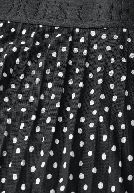Une jupe noire à pois blancs avec une ceinture élastique portant l'inscription 'SPORTS CLUB'.