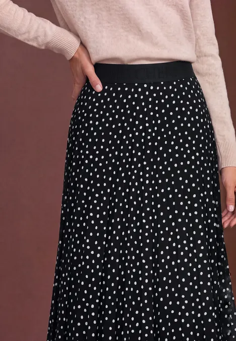 Jupe noire fluide à pois blancs, portée avec un haut rose pâle
