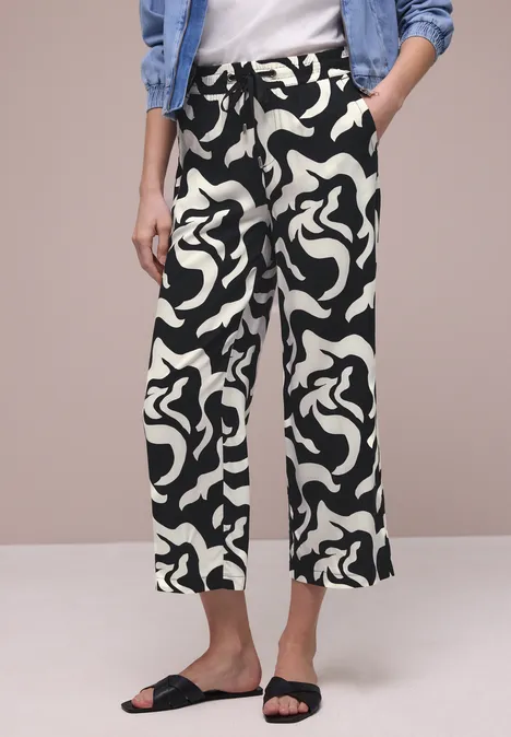 Zwart-witte, wijdvallende broek met abstract patroon, gecombineerd met een wit topje en zwarte sandalen.