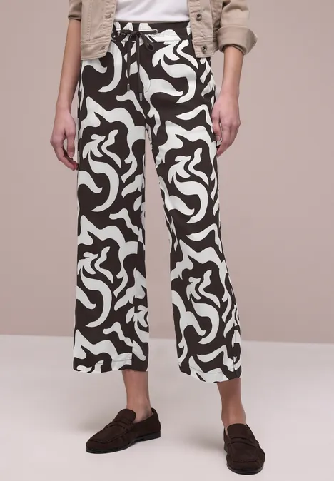 Zwart-witte culotte met abstract patroon, hoge taille en wijde pasvorm, gecombineerd met donkere loafers.