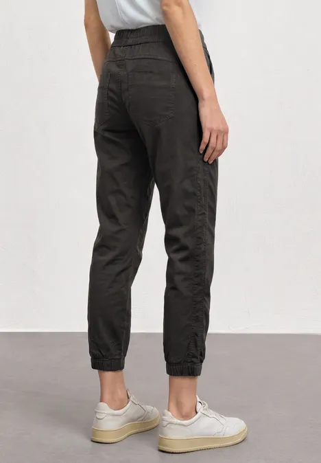 Slim Leg Hose in Papertouch-Qualität deep earth Dunkle Joggerhose mit hohen Bündchen, locker sitzend, kombiniert mit weißen Sneakern, Rückansicht.