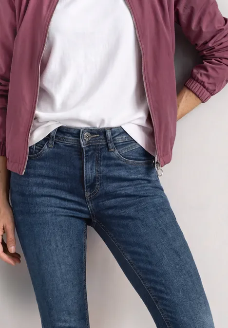 Mid Waist Slim Leg Jeans im Slim Fit brilliant indigo random wash Person trägt blau-enge Jeans, weißes T-Shirt und burgunderrote Jacke
