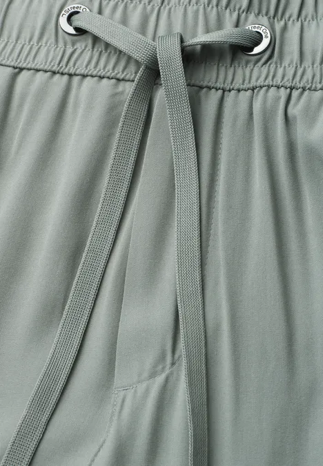 Close-up van een grijsgroene broek met aantrekkoord en elastische taille