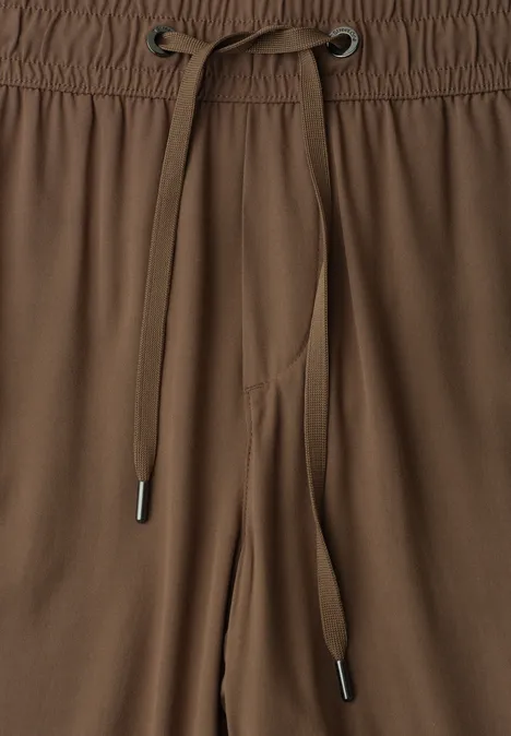 Braune Freizeithose mit Tunnelzug und elastischem Bund, silberne Metallenden an den Kordeln.