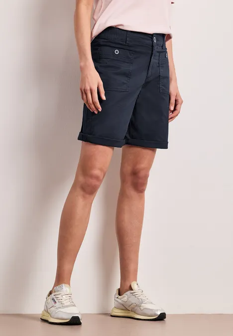 Kurze dunkelblaue Bermudashorts und weiße Sneaker an einem Model