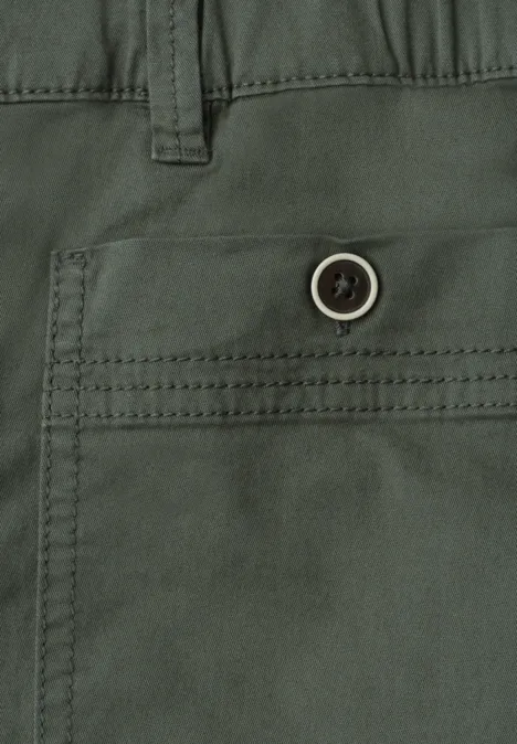 Nahaufnahme einer grünen Hose mit seitlicher Tasche und Knopf.