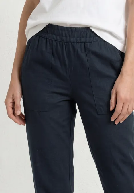 Frau trägt navyblaue, lässige Hose mit Gummizugbund und Seitentaschen vor weißem Hintergrund.